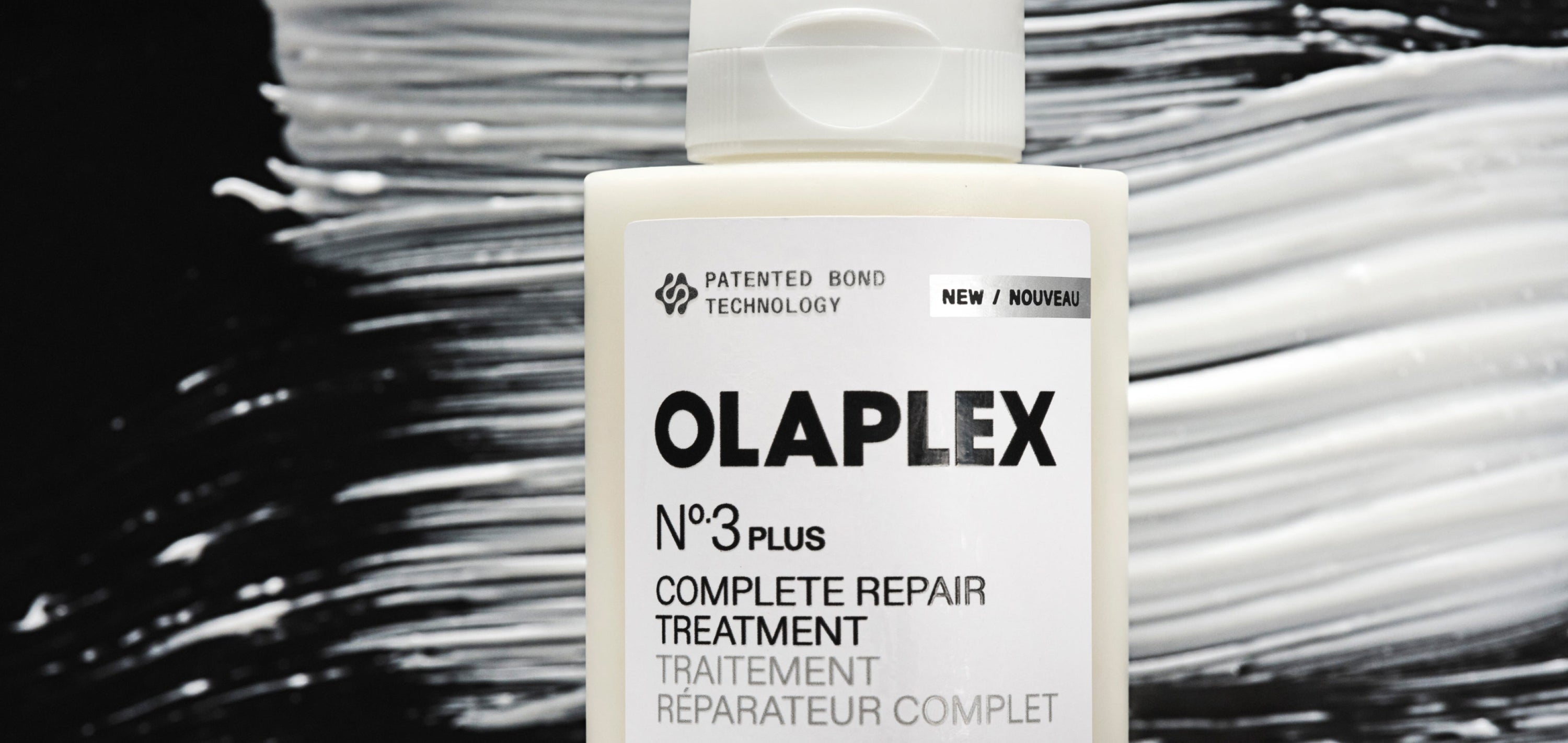 A bottle of OLAPLEX No.3PLUS Hair Repair treatment in front of a smear of the product 