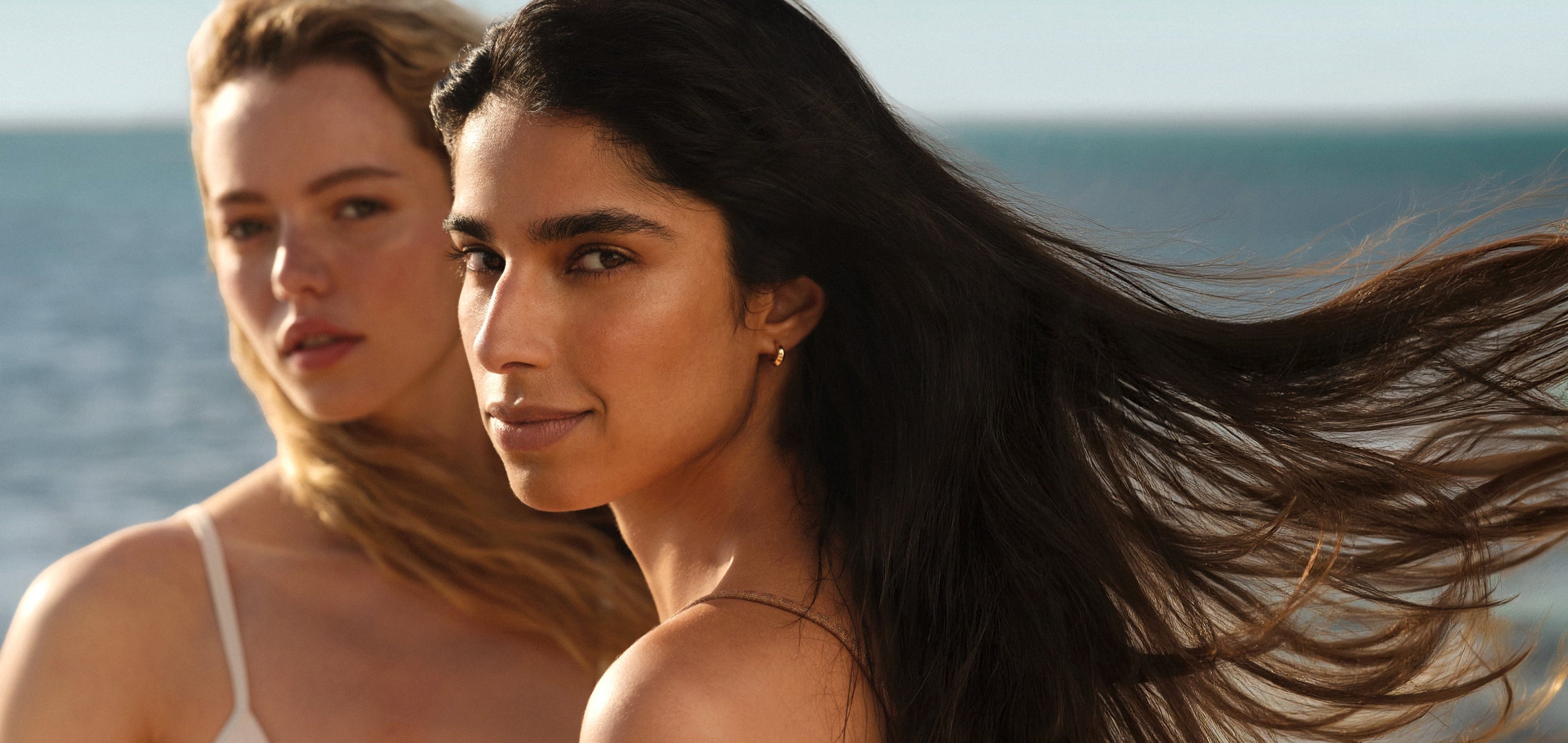 Two women standing near the ocean