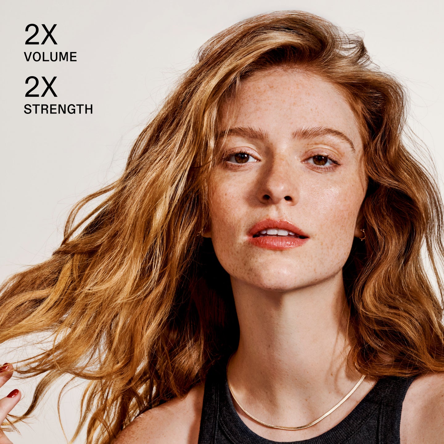 Woman with styled hair against a plain background with text '2X Volume' and '2X Strength'.