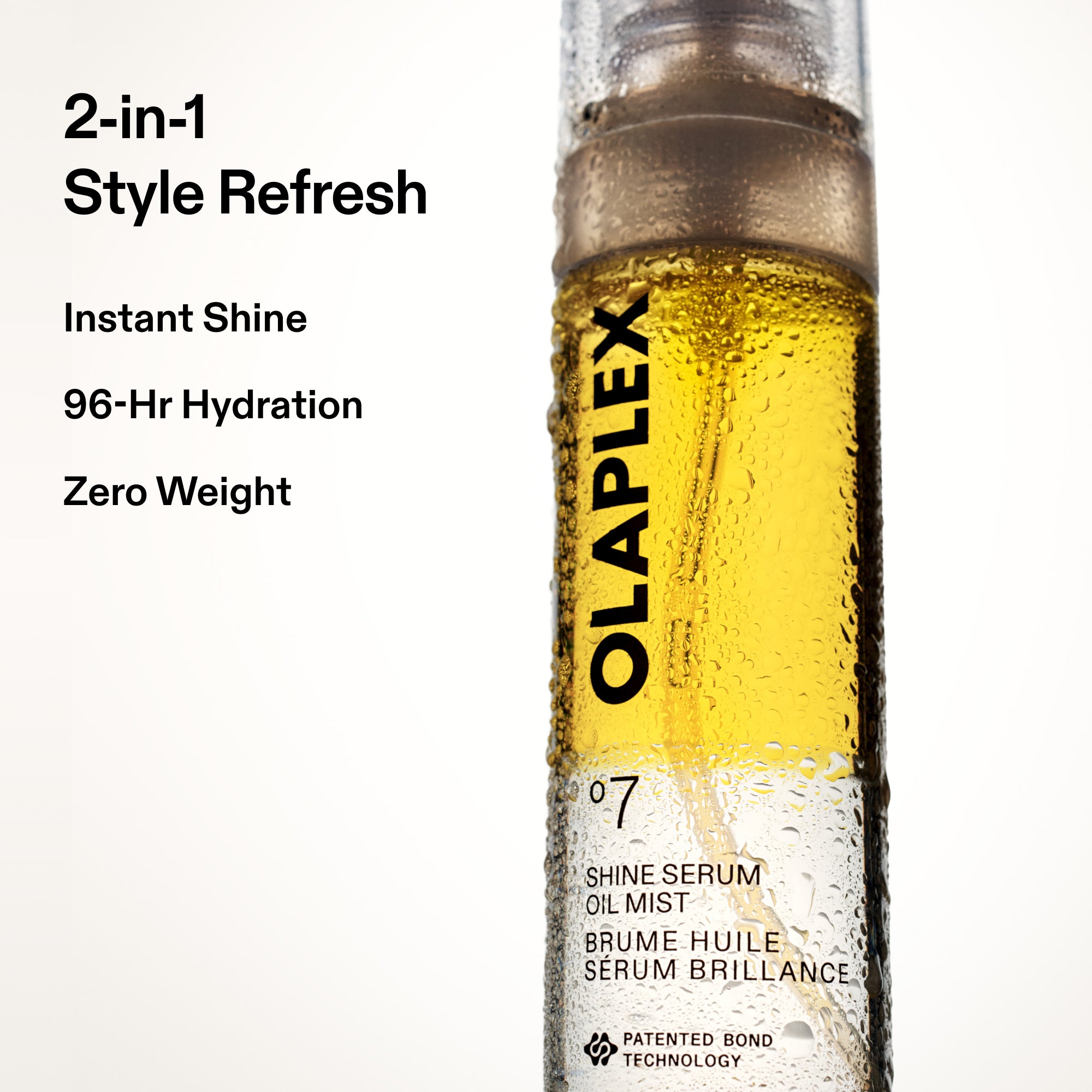 A product graphic on a white background featuring a close-up shot of the Olaplex No. 7 Shine Serum Oil Mist bottle. Bold black text to the left of the bottle reads: "2-in-1 Style Refresh", followed by "Instant Shine", "96-Hr Hydration", and "Zero Weight". The clear bottle showcases the vibrant golden-yellow serum mist inside, covered in light condensation.